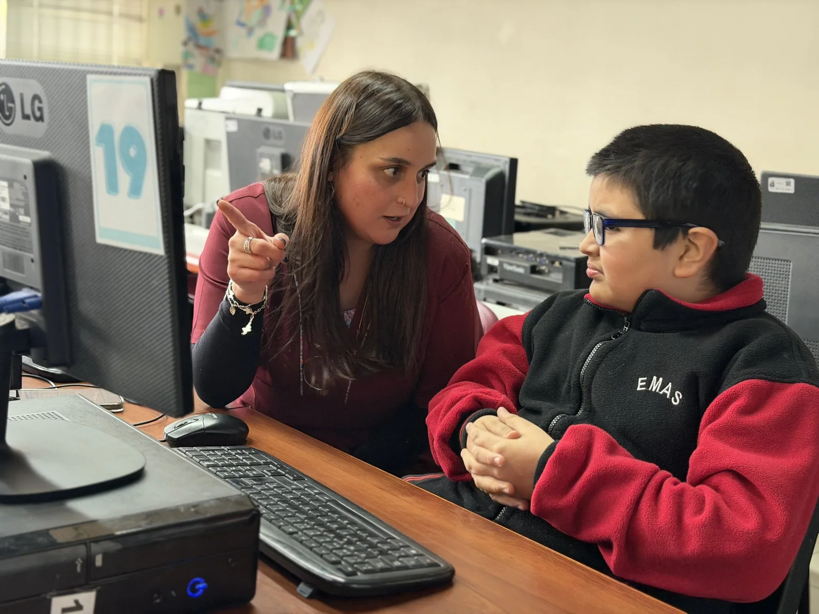 Profesional de Educación Diferencial acompañando a un estudiante durante una actividad en el computador